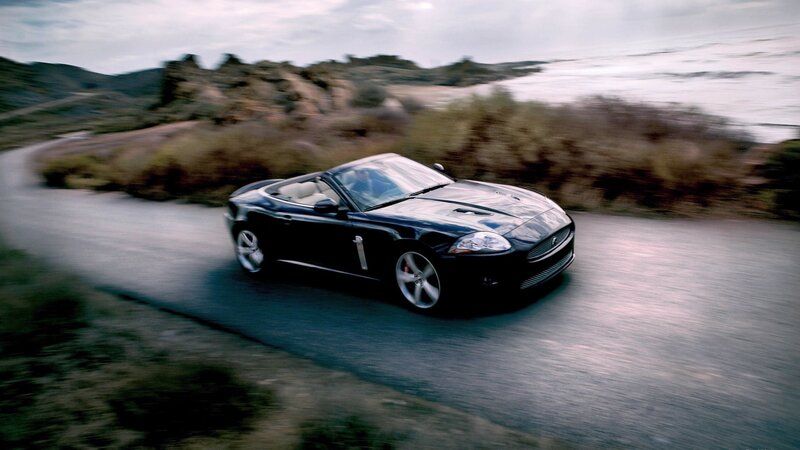 black jaguar convertible on coastal road