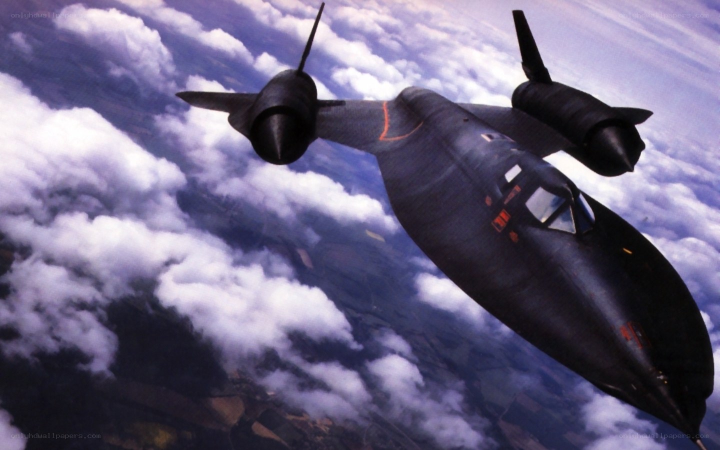 Black jet flying above clouds