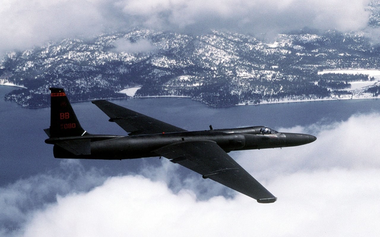 Black jet flying over mountains