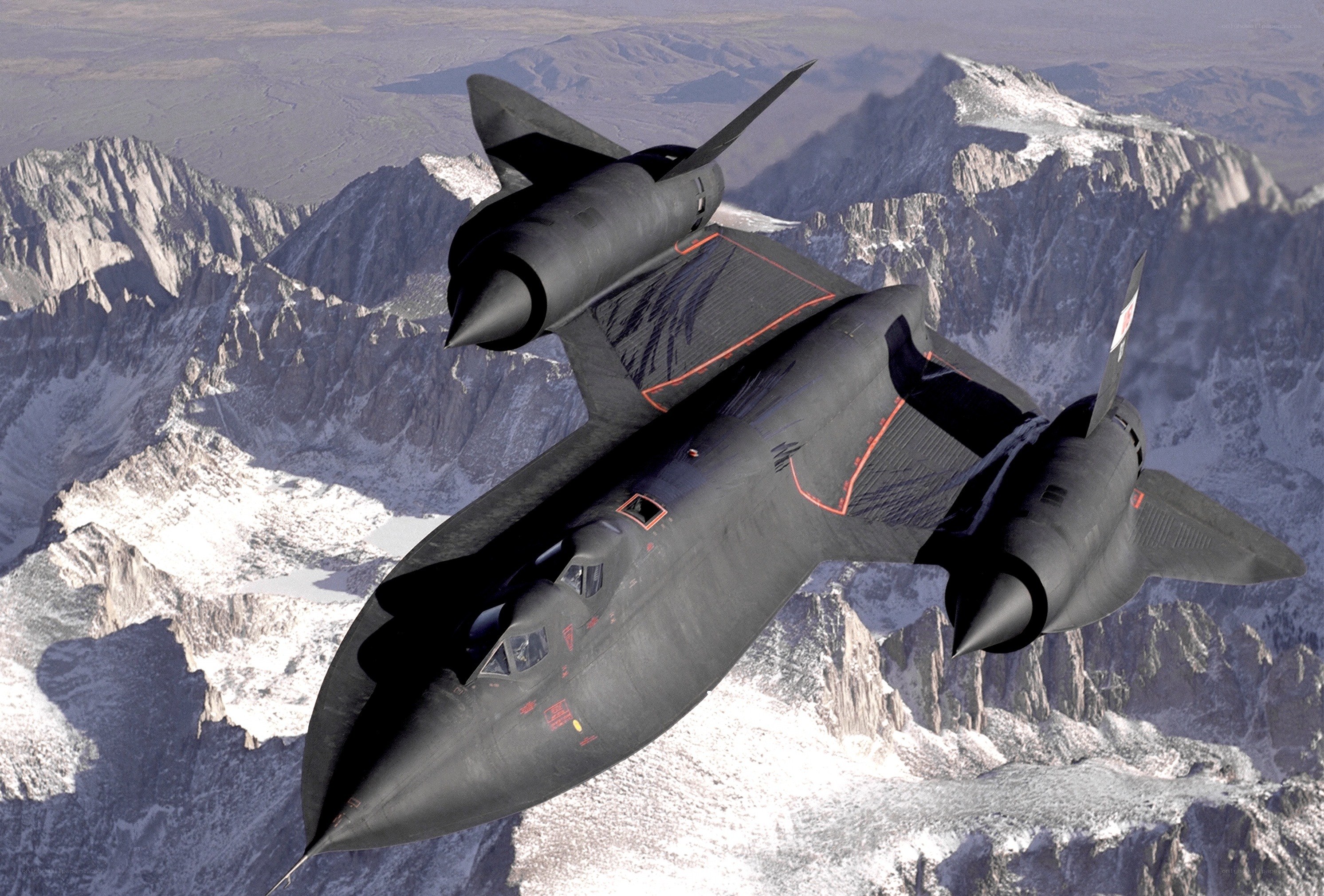 Black jet flying over mountains