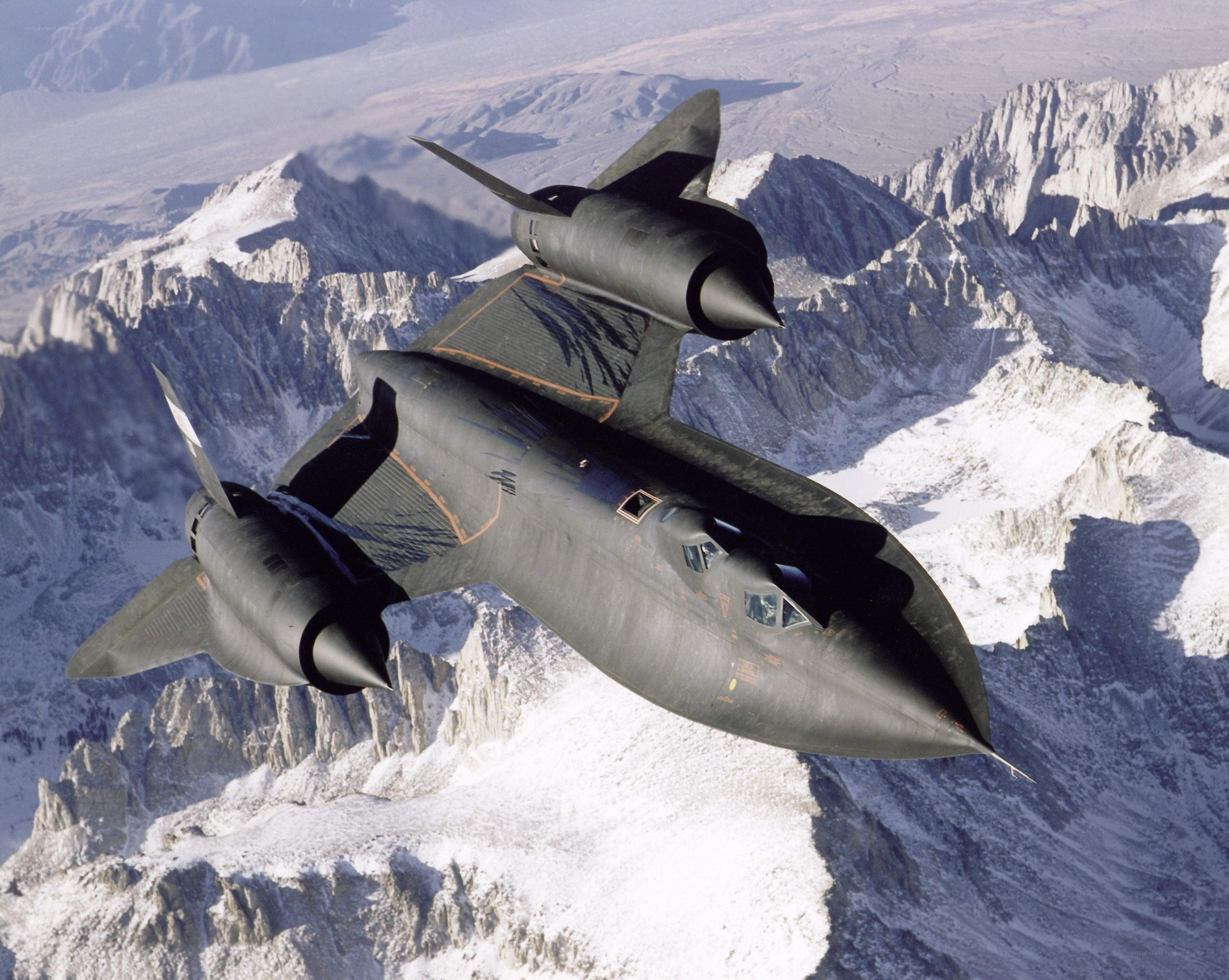 Black jet flying over mountains