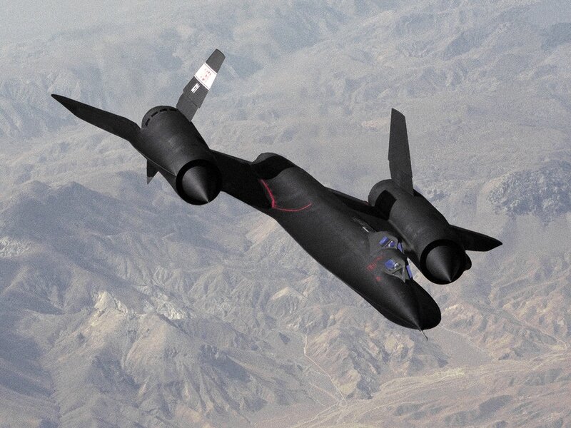 Black jet flying over mountains
