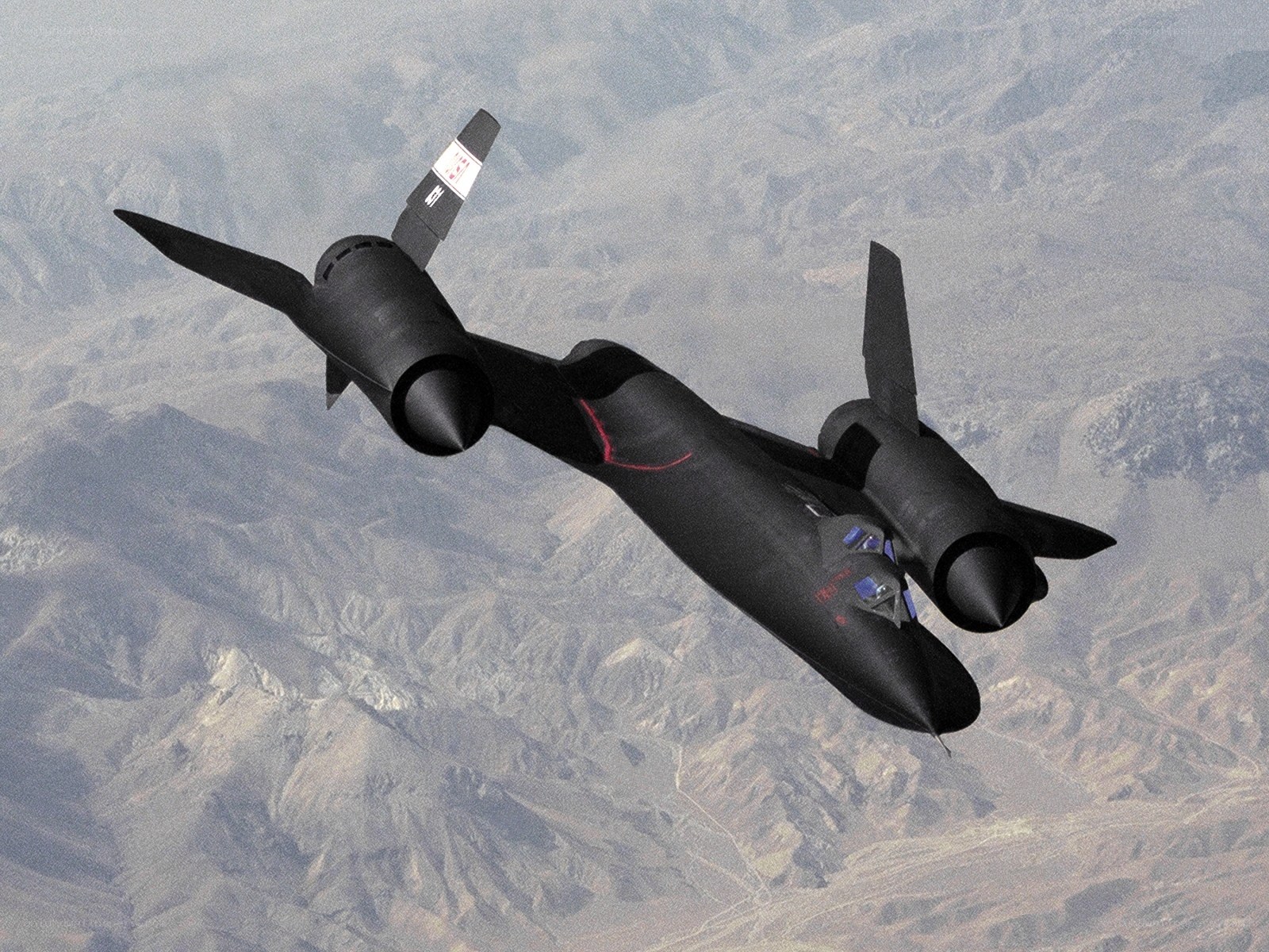 Black jet flying over mountains