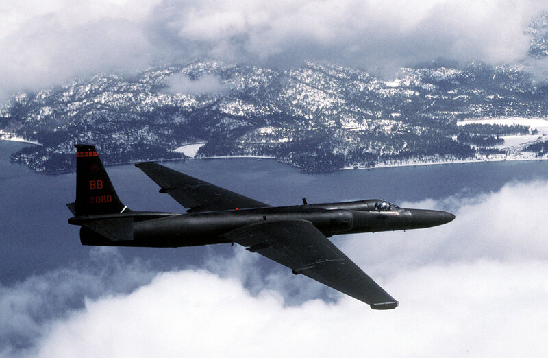 Black jet flying over snowy mountains