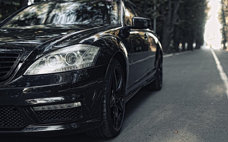 black luxury sedan on a tree-lined road