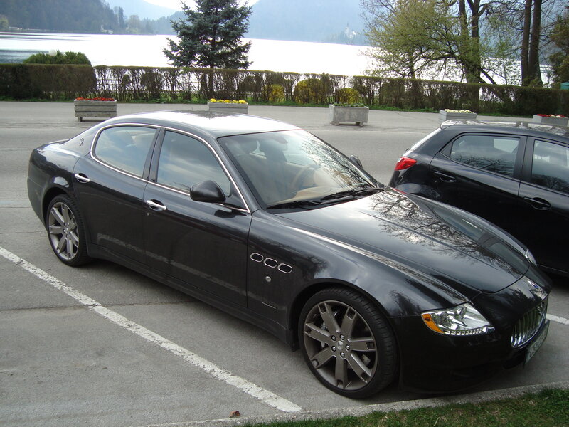 Black Maserati parked by a lake