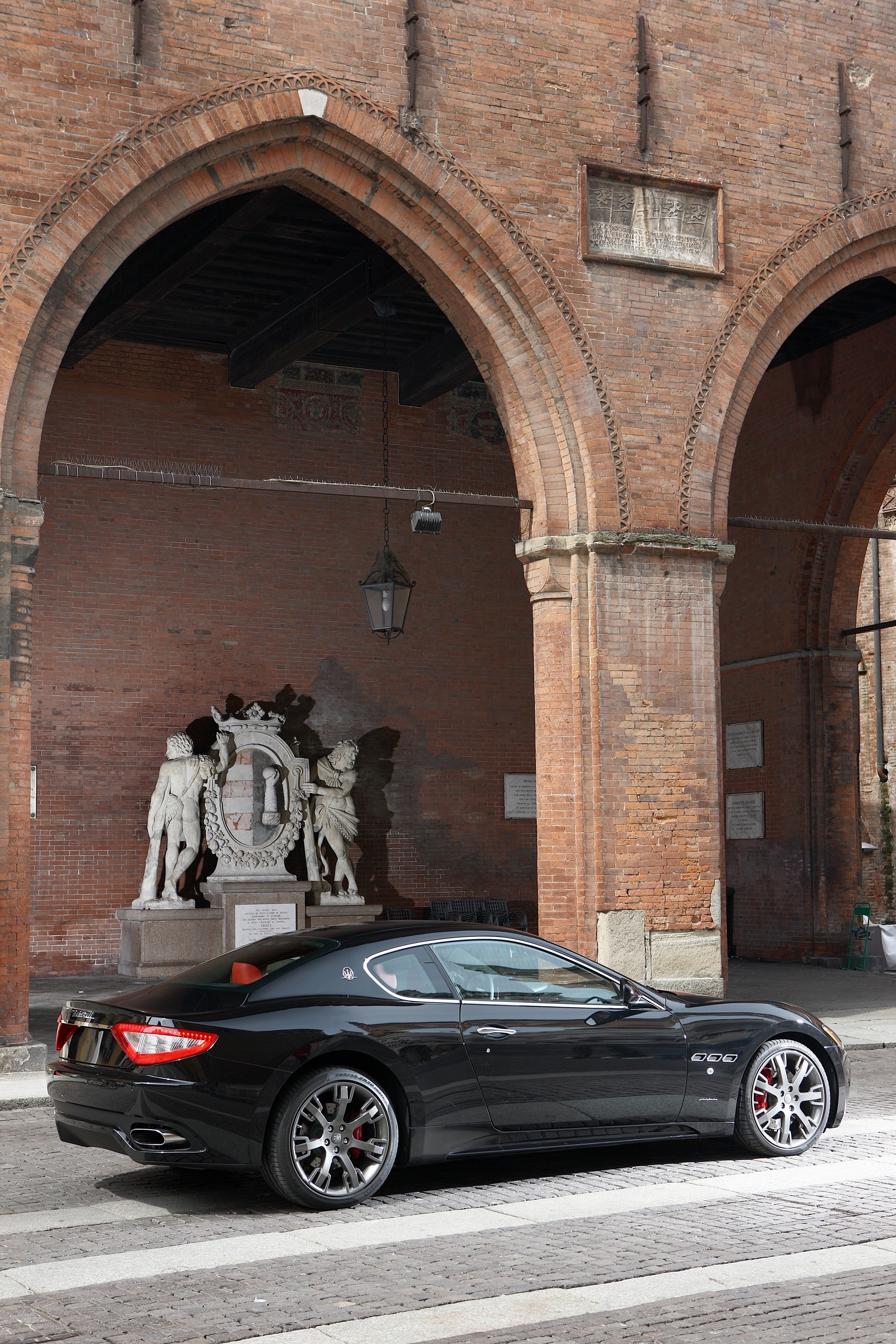Black Maserati under brick arches