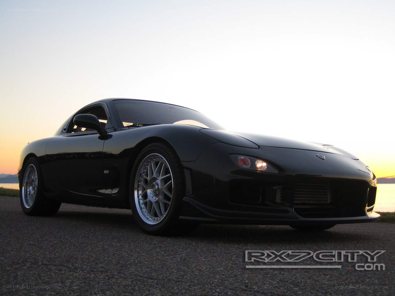 Black Mazda RX-7 at sunset