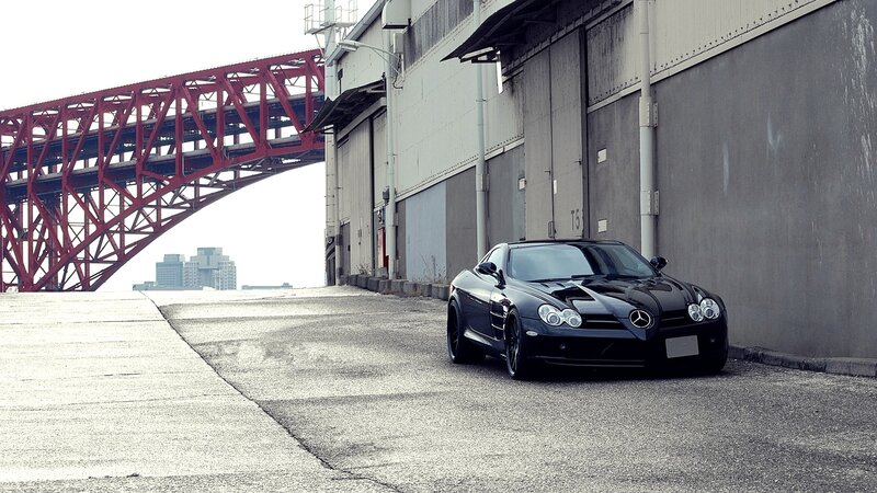 Black Mercedes SLR parked by bridge