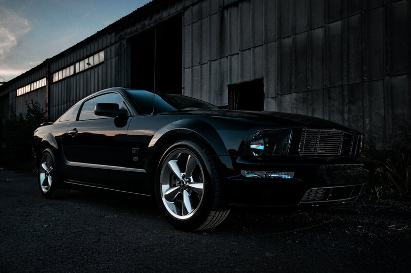 black mustang in front of warehouse
