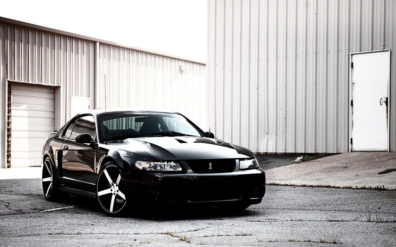 black mustang in front of warehouse