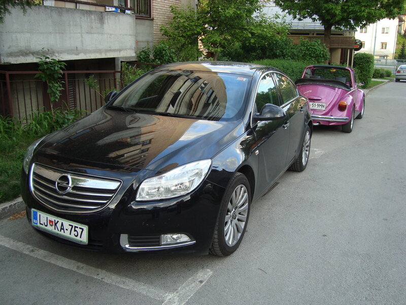 Black Opel and pink Beetle parked