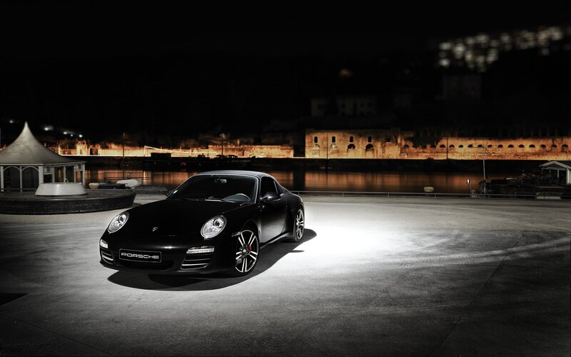 Black Porsche at night by the water