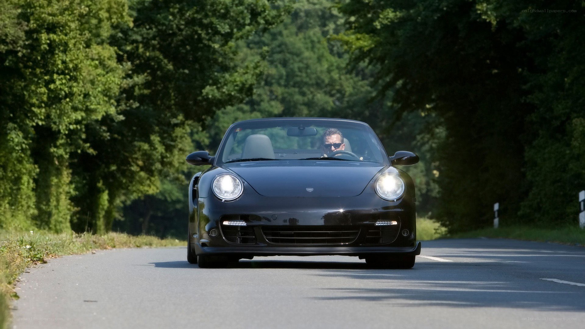 Black Porsche convertible on a road