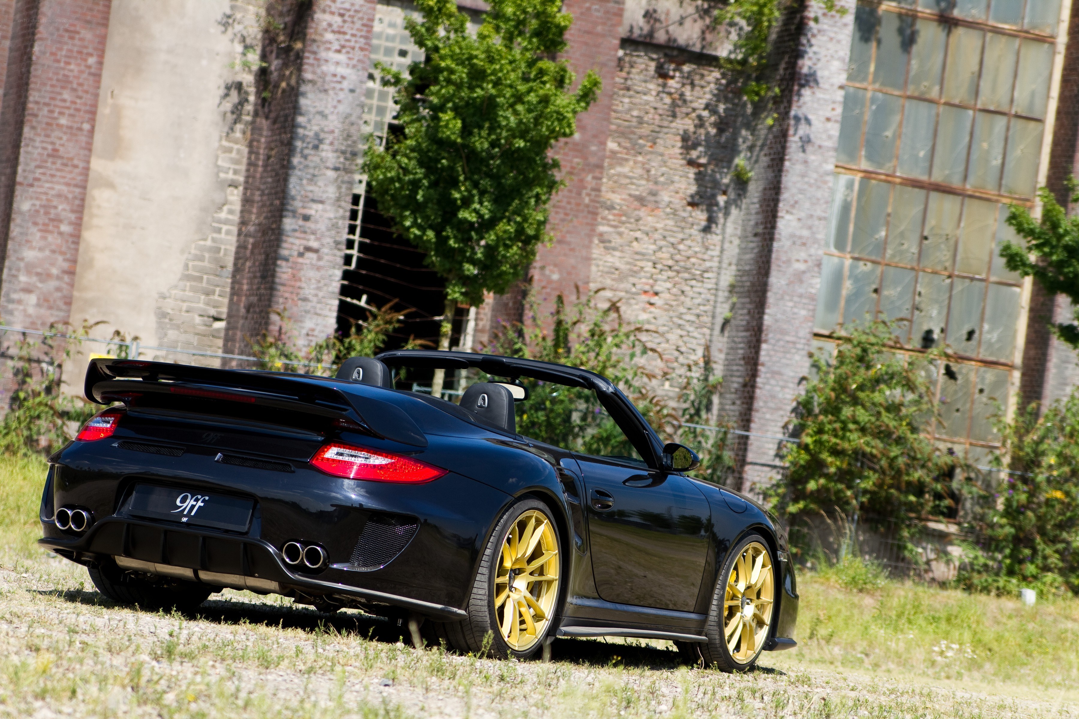 Black Porsche convertible with gold wheels