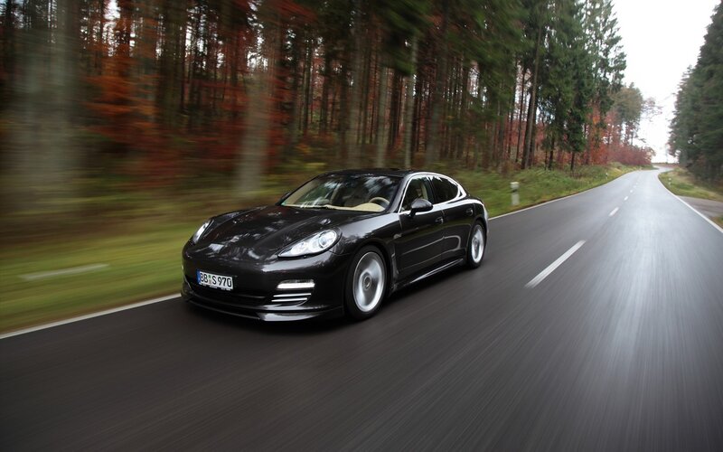 Black Porsche driving on forest road