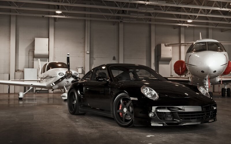 Black Porsche in airplane hangar