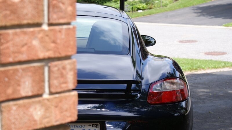 Black Porsche parked near brick wall