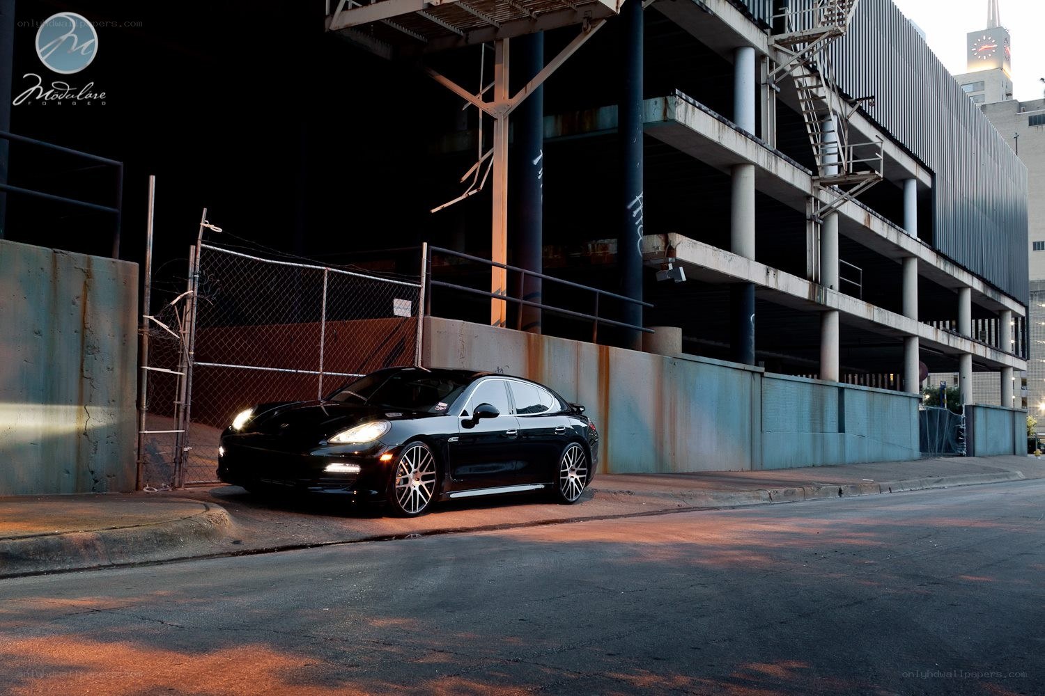 Black Porsche parked under a bridge