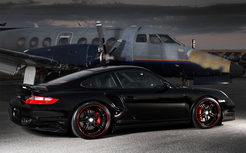 Black Porsche with airplane in background