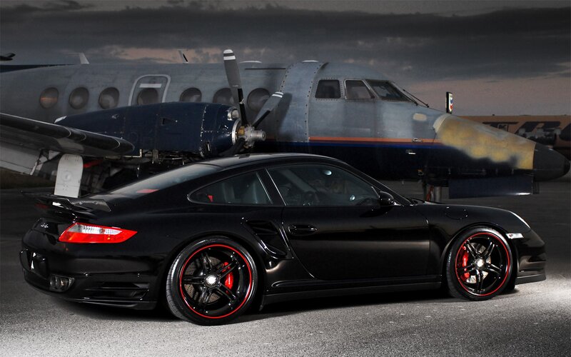 Black Porsche with airplane in background
