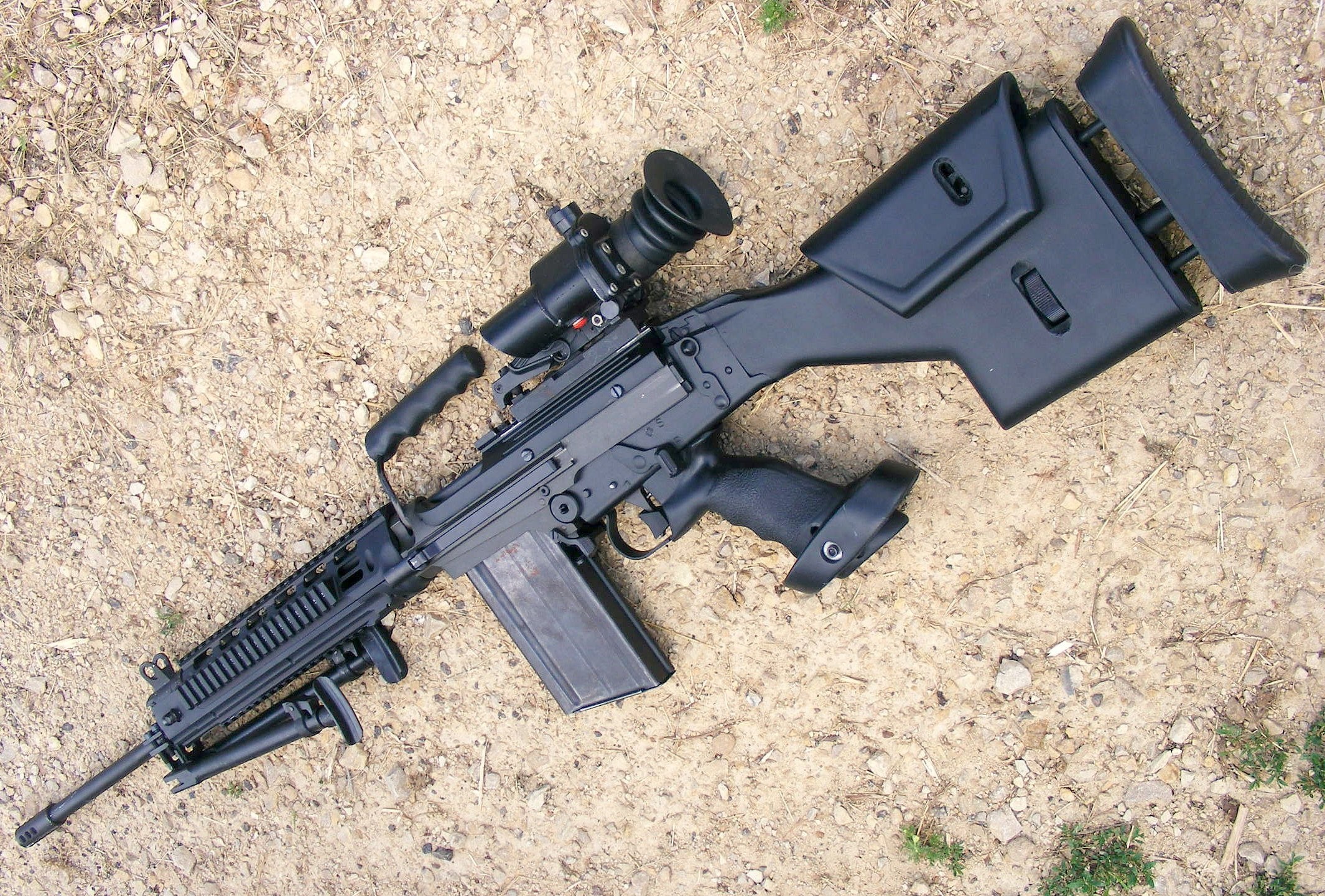Black rifle with scope on ground