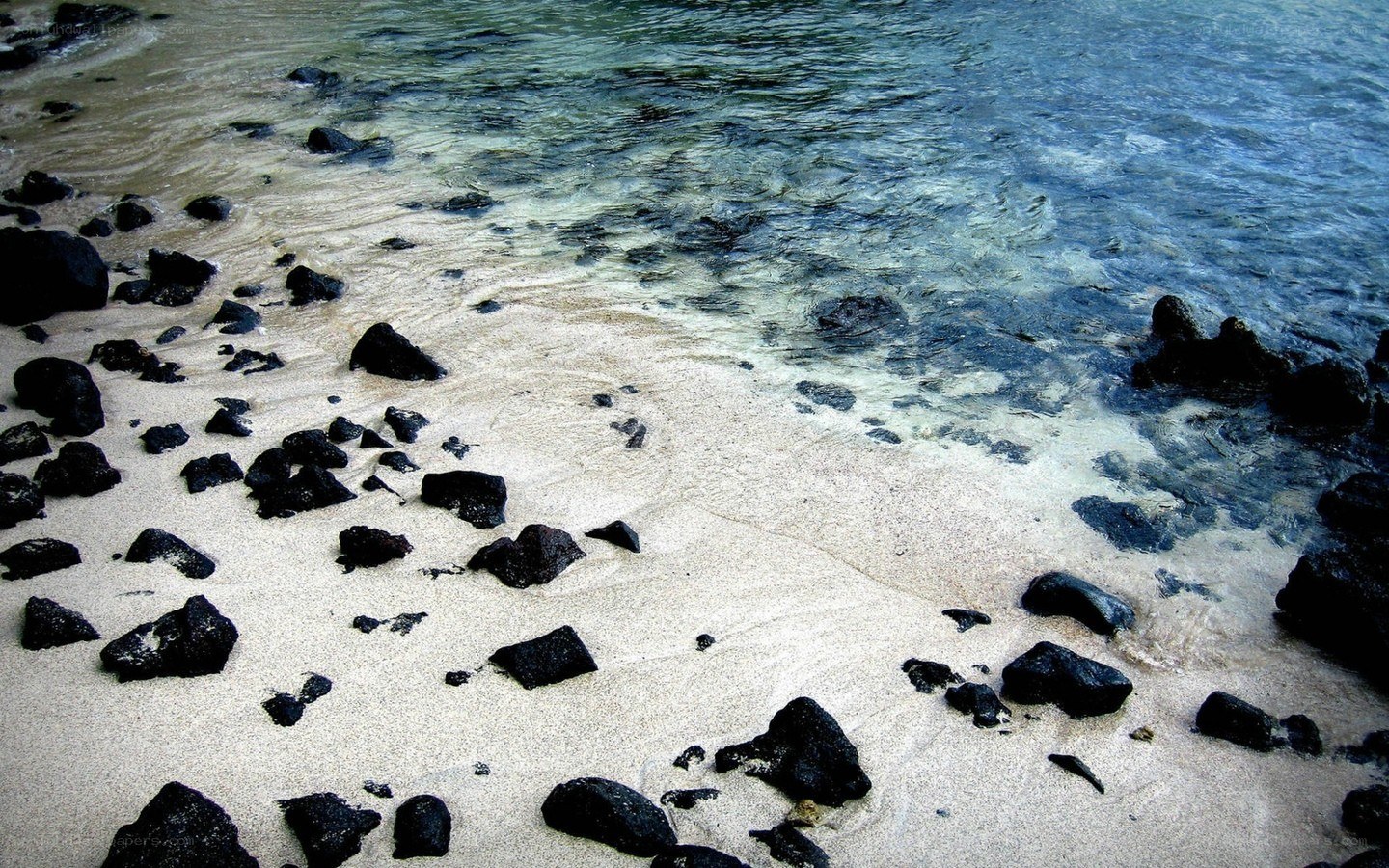 black rocks on sandy beach