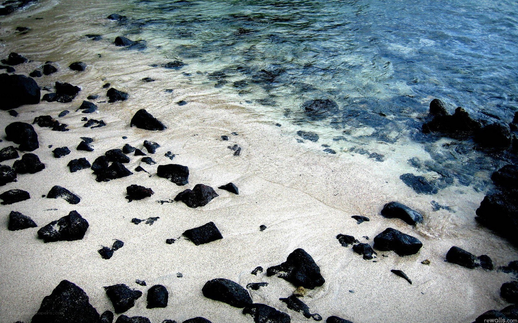 black rocks on sandy beach
