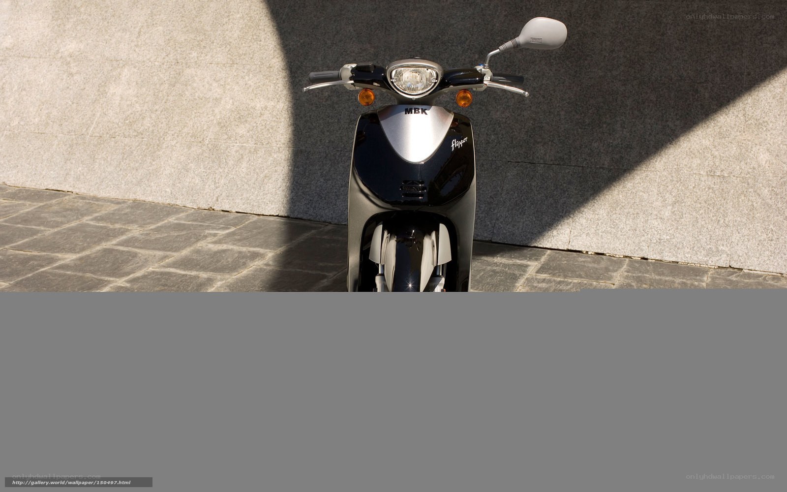 Black scooter against stone wall
