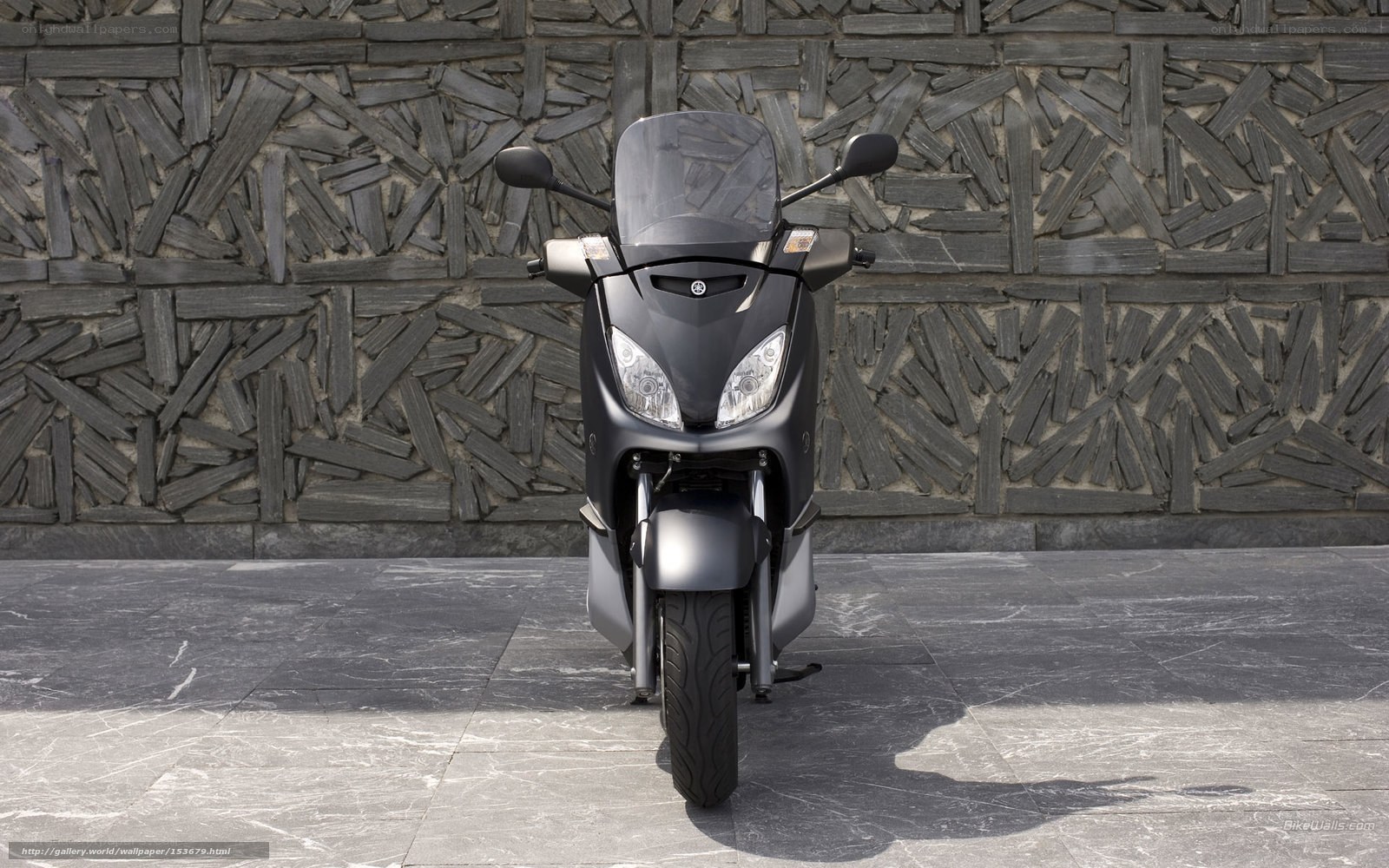 Black scooter on stone wall