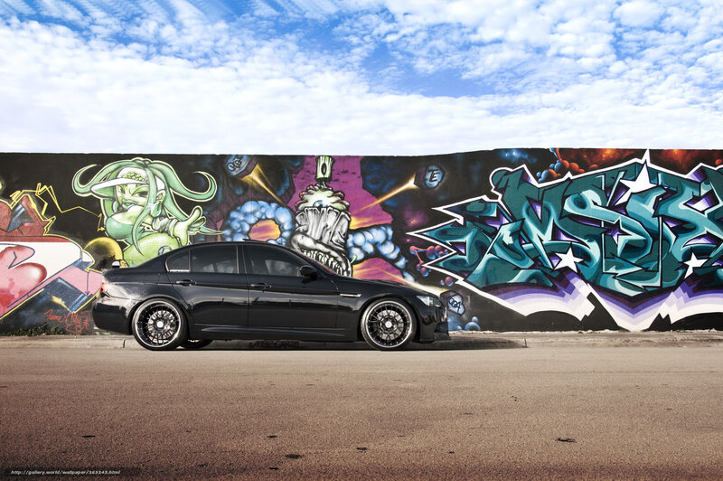 Black sedan in front of graffiti wall