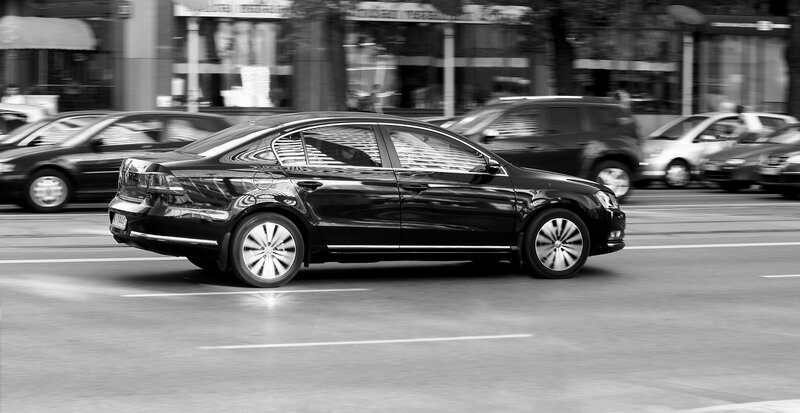 Black sedan in motion on city street