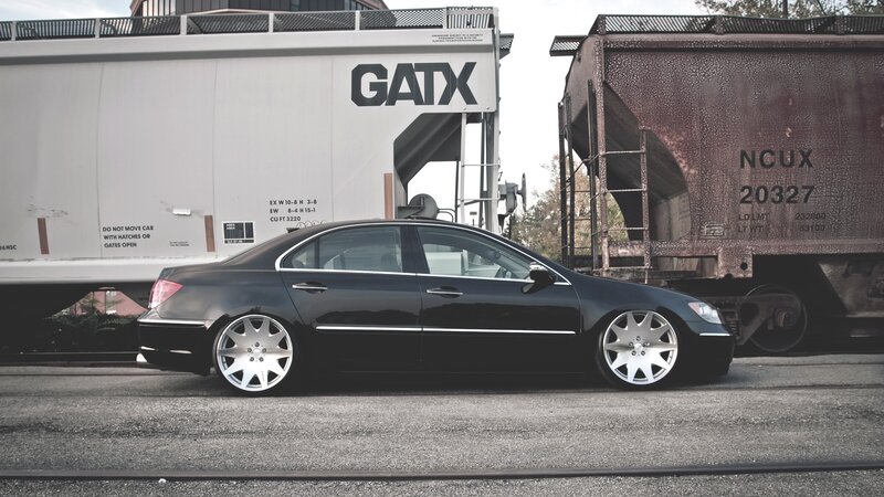 black sedan near train cars