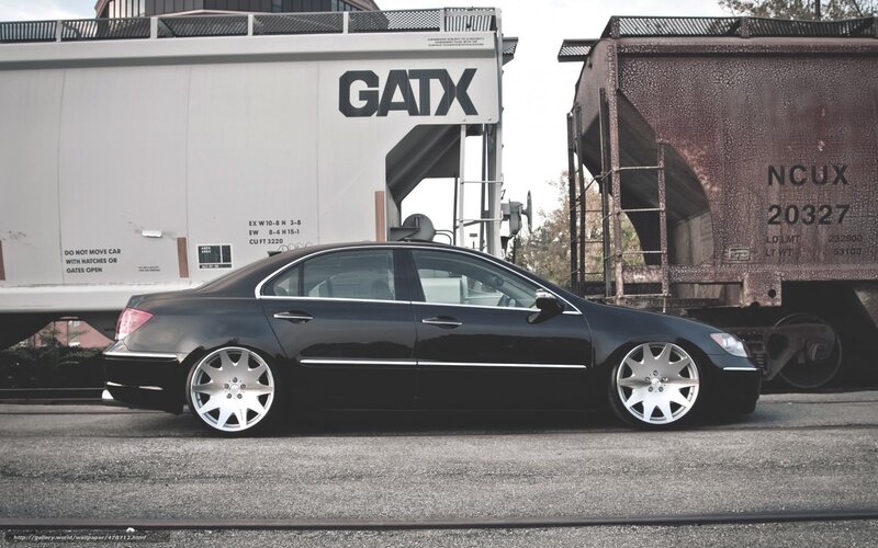 black sedan near train cars
