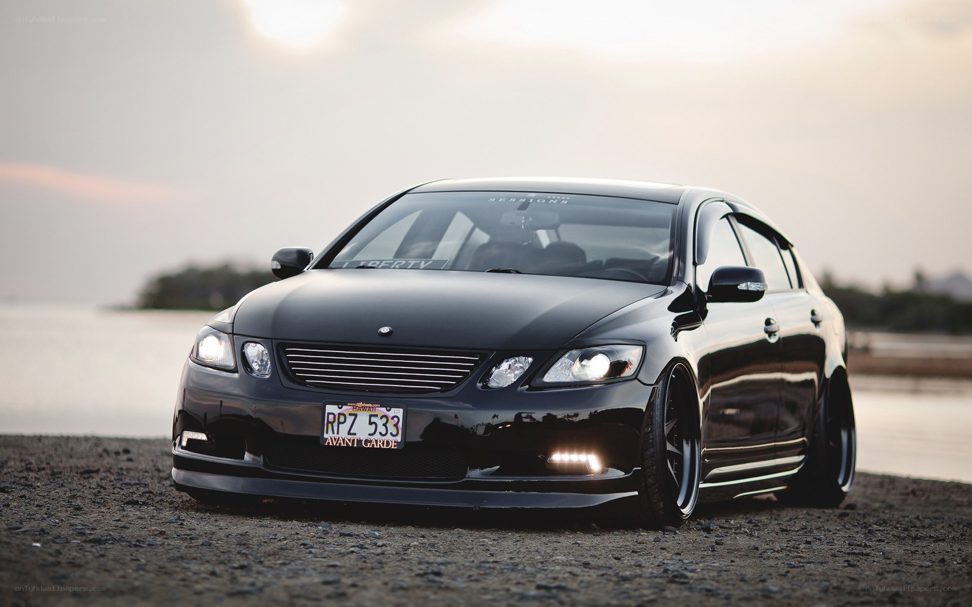 black sedan on beach at sunset