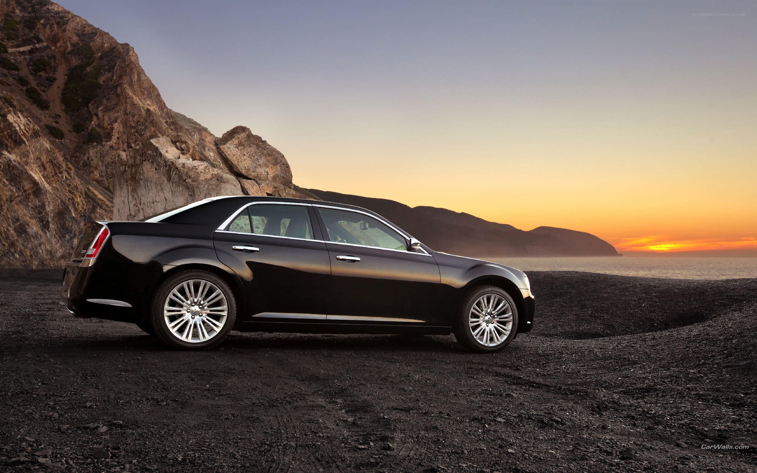 Black sedan on beach at sunset