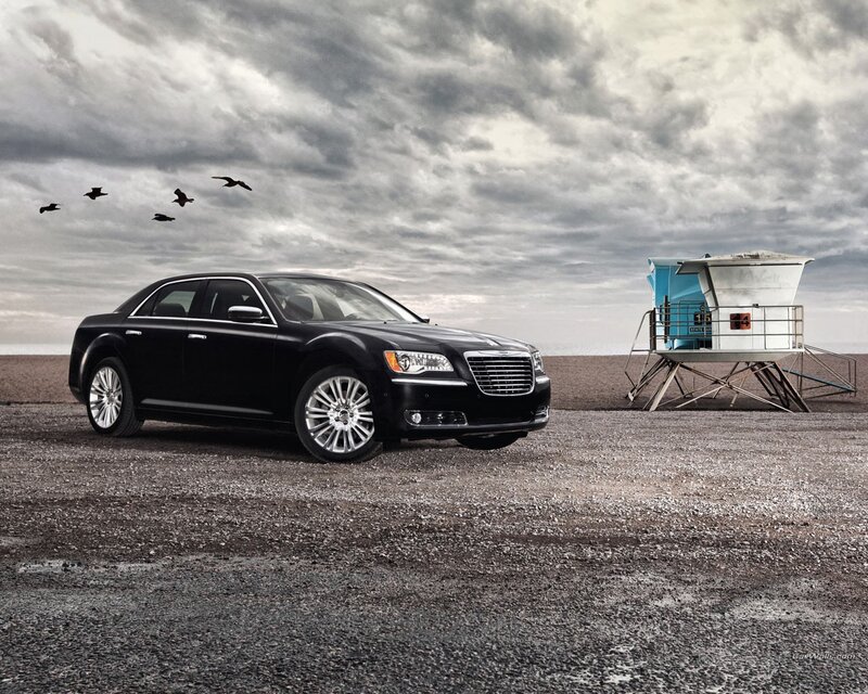 Black sedan on beach with lifeguard tower