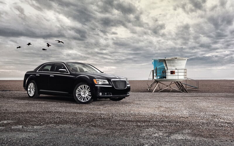 Black sedan on beach with lifeguard tower