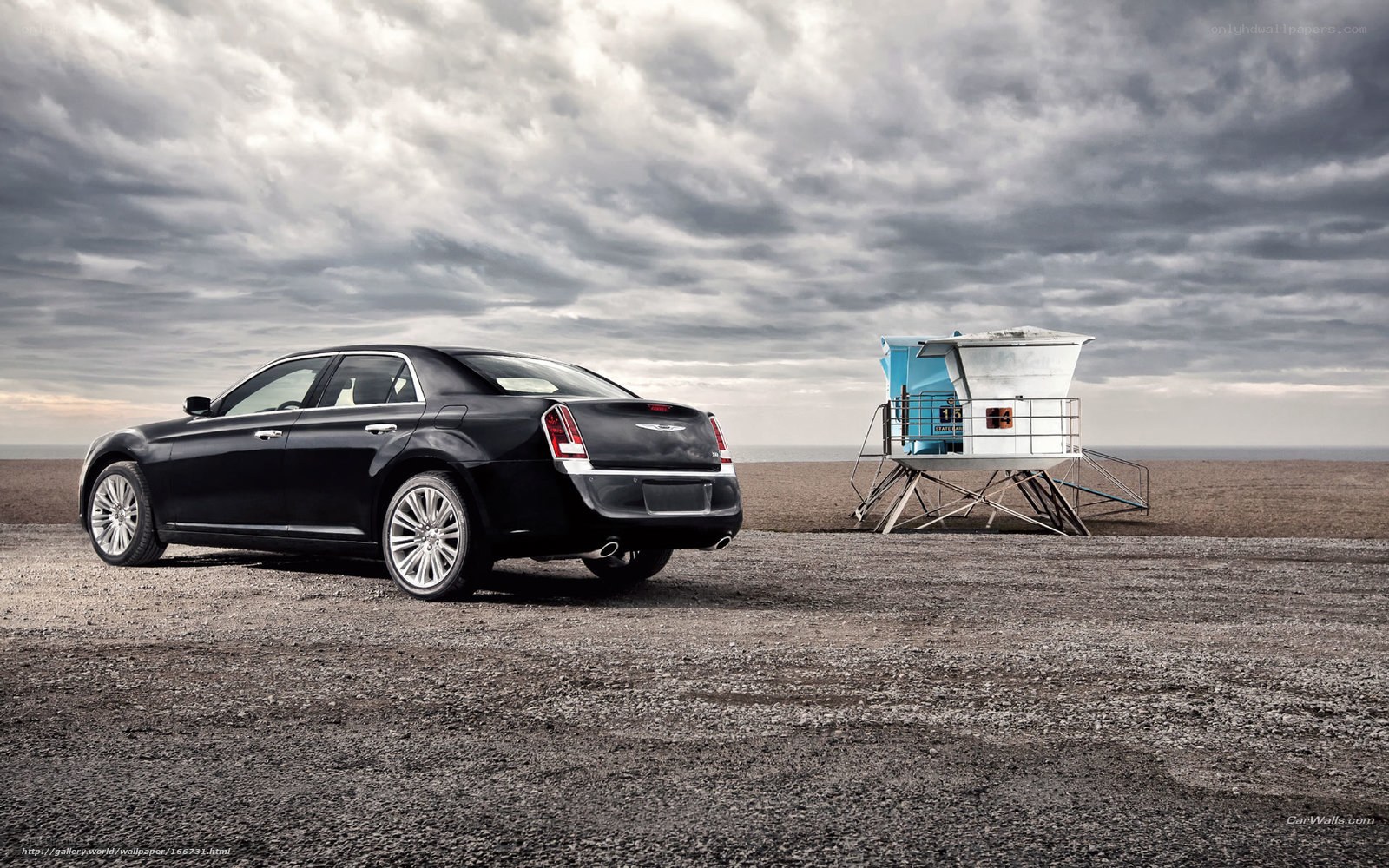 Black sedan on beach with lifeguard tower