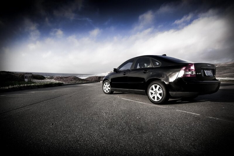 Black sedan on coastal road