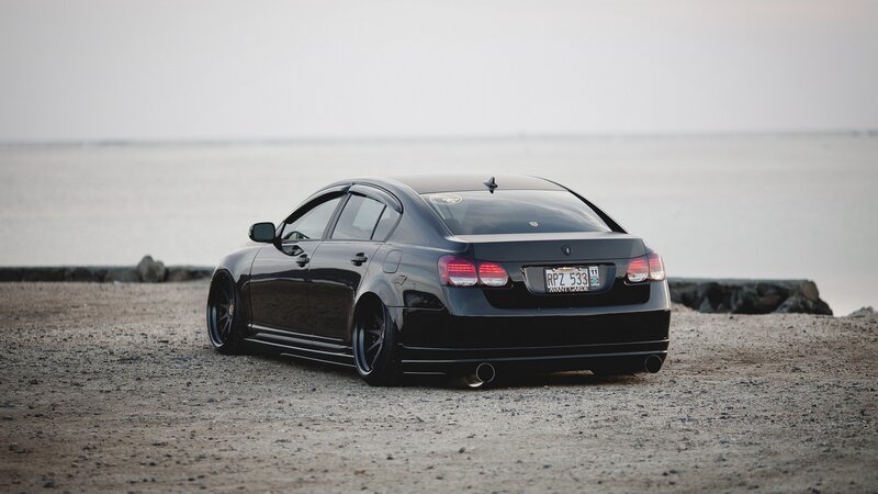 black sedan on gravel beach