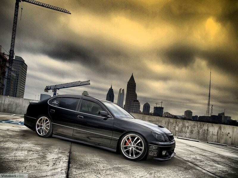 Black sedan on rooftop with city skyline