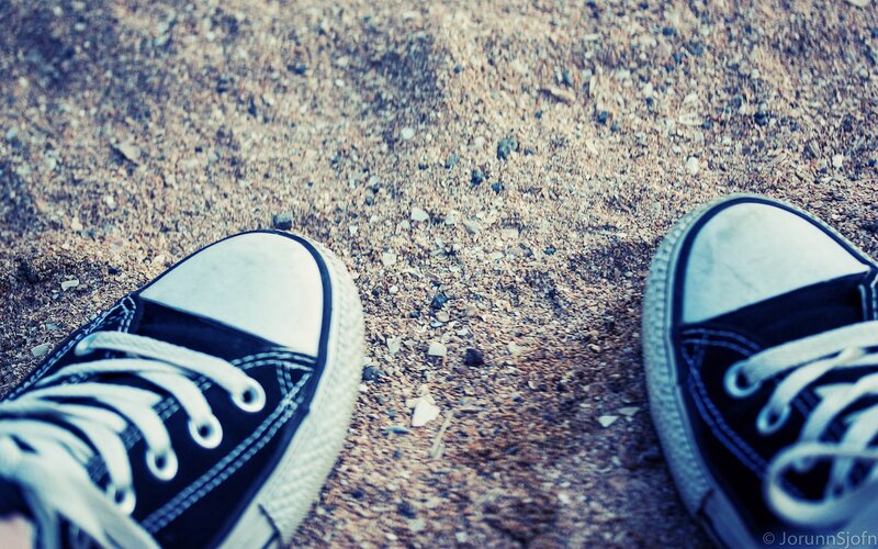 black sneakers on gravel