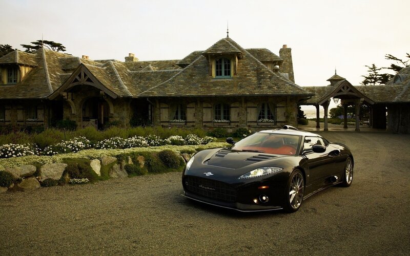 Black sports car in front of mansion