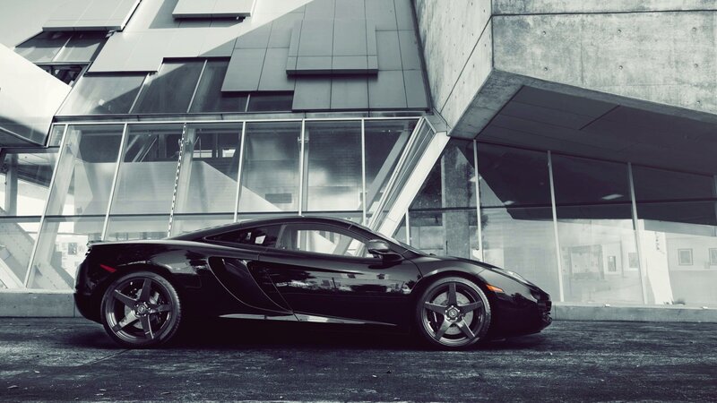 Black sports car in front of modern building