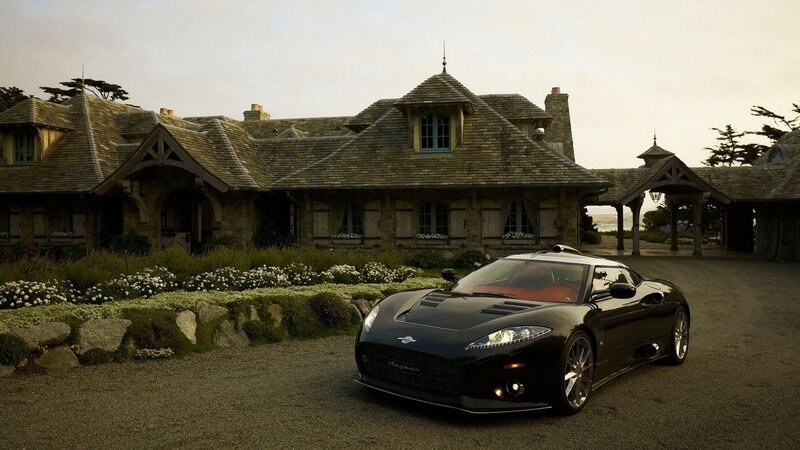 Black sports car in front of stone house