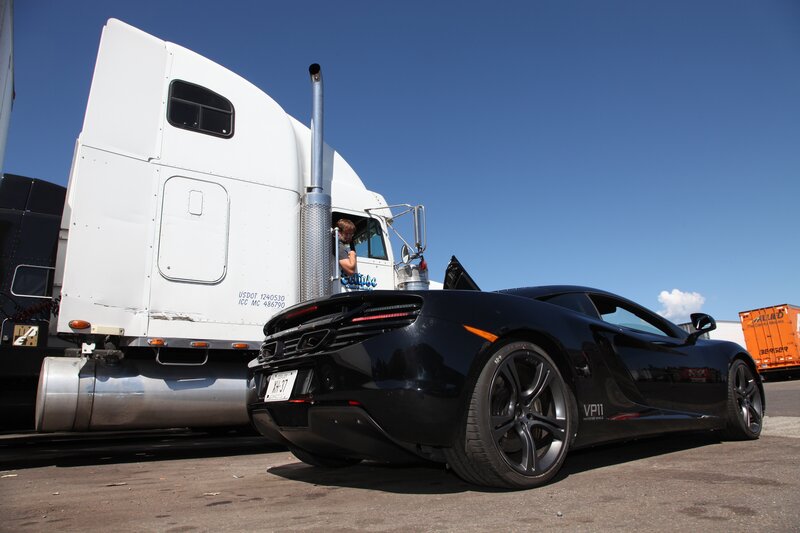 Black sports car next to a semi-truck