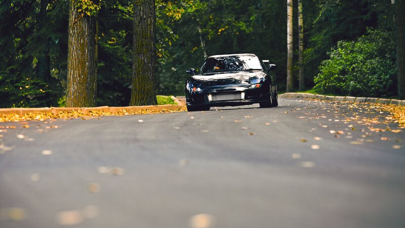Black sports car on a forest road