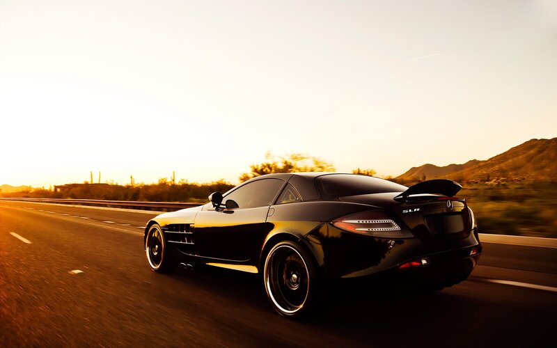 Black sports car on highway at sunset
