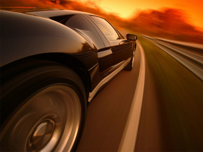 Black sports car on road at sunset